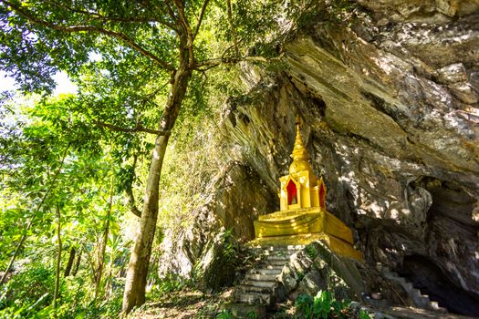 golden pagoda infront of natural cave in the forest,Chiangrai,Thailand