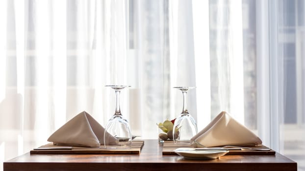 A simple and beautifully arranged table for two, with cloth napkins and wine glasses