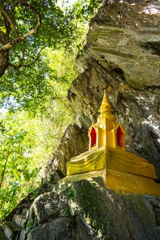 golden pagoda infront of natural cave in the forest,Chiangrai,Thailand