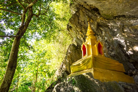 golden pagoda infront of natural cave in the forest,Chiangrai,Thailand