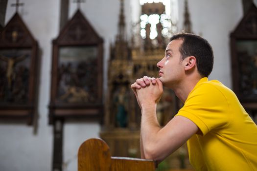 Handsome young man praying in a church