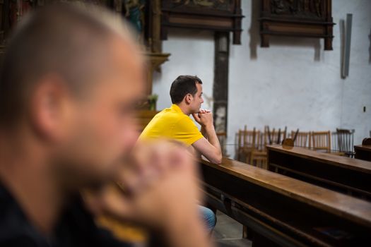 Handsome young man praying in a church