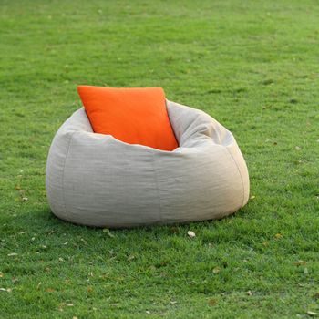 Fabric chair with pillow on green grass