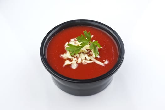 Tomato soup isolated on white with a basil garnish. Clipping path included.