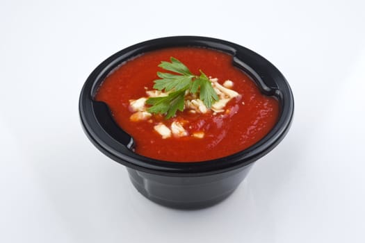 Tomato soup isolated on white with a basil garnish. Clipping path included.