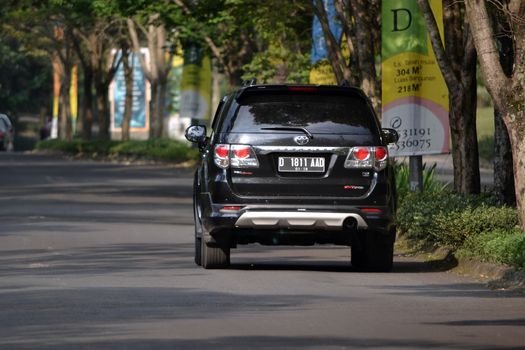 bandung, indonesia-june 9, 2014-black colored toyota fortuner cruising on the road