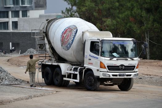 bandung, indonesia-june 9, 2014-indocement concrete mixer truck parking in front of unfinished luxury hotel building