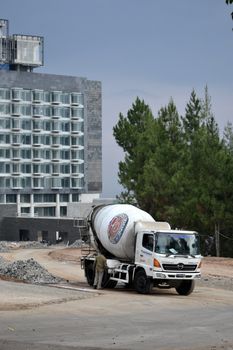 bandung, indonesia-june 9, 2014-indocement concrete mixer truck parking in front of unfinished luxury hotel building