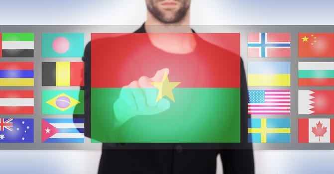Hand pushing on a touch screen interface, choosing language or country, Burkina Faso