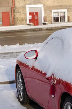 close up of red new car side abundantly covered with snow outdoor in parking