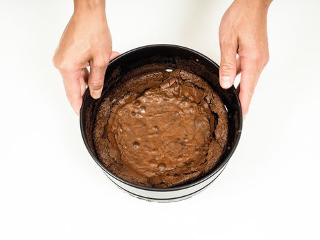 Person removing a round shape from fresh made chocolate cake