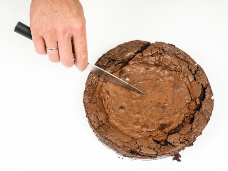 Person cutting a fresh made chocolate cake with a knife