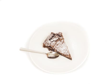 Piece of fresh made chocolate on plate with powdered sugar and teaspoon
