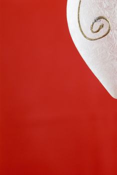 A white frosted glass Christmas decoration on red background