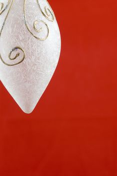 A white frosted glass Christmas decoration on red background