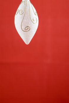 A white frosted glass Christmas decoration on red background