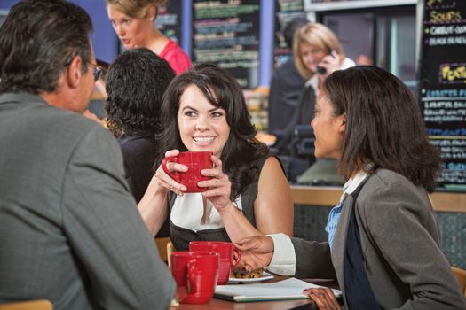 Attractive woman and coworkers with coffee cups in restaurant