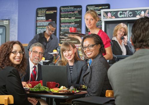 Barista serving diverse group of smiling business people