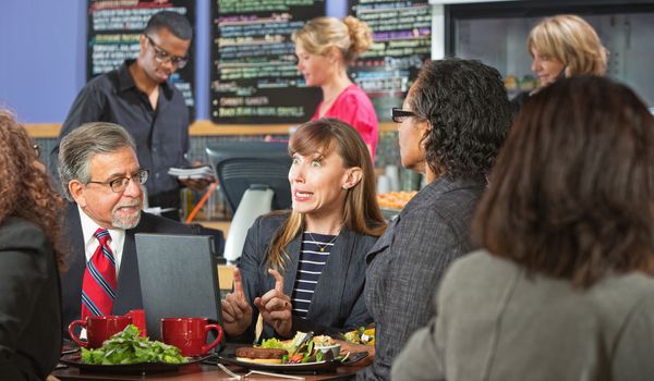 Excited business woman with coworkers and laptop in cafe