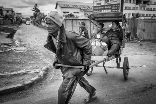 Antsirabe, Madagascar – May 24: - Malagasy people hire a Pousse-Pousse (rickshaw) for their daily commute on May 24, 2014 in Antsirabe, Madagascar.