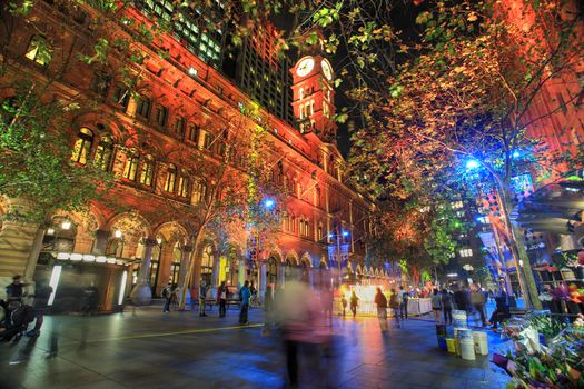 SYDNEY, AUSTRALIA - JUNE 6, 2014;   Martin Place, A CBD and shopping disrict of Sydney lit up in various ever changing colour, during annual Vivid festival.  People in motion.  Sky flower in distance.