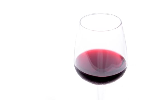 Red wine pouring in a wineglass on white background