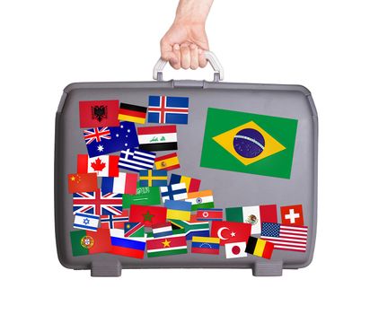 Used plastic suitcase with lots of small stickers, large sticker of Brazil