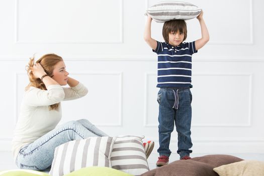 Cute, adorable boy with mother fighting with pillows