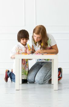 Cute, adorable boy with mother painting on the floor