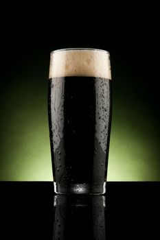 glass of black beer with reflection and water drops