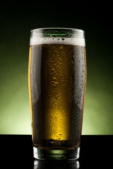 back lit glass of beer with water drops