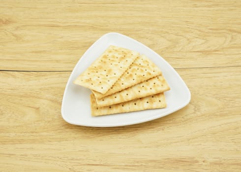 Crackers on a white plate, have square shape, put on table.                                