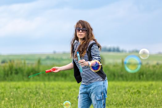 Beautiful Young Woman make Blowing Bubbles, on green grass