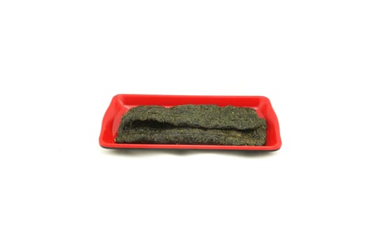 Fried seaweed, thin pieces, rectangular shape. Placed in red dish, delicious and health benefits.                             