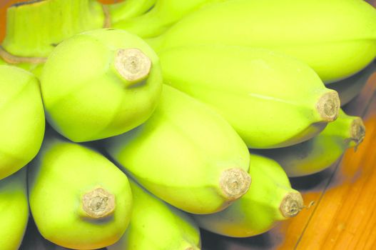 A raw banana, have large size, green colour, delicious, and beneficial to the body. Placed on a wooden table.                             