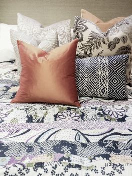 Close-up of a bed with lots of colorful pillows.