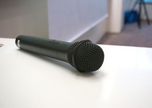 Black microphone lying on white table. In front of the classroom                              