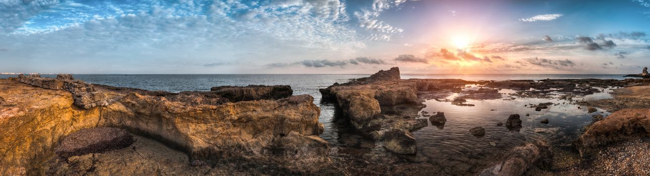 Sunset over the Sea and Rocky Coast with Ancient Ruins