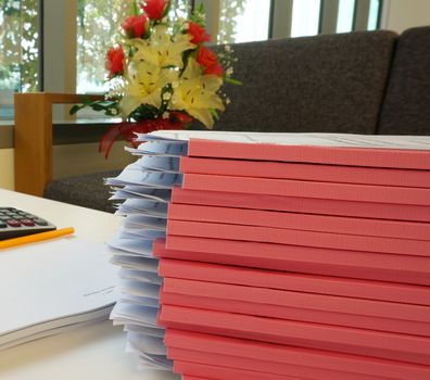 Pile of document that cover with pink colors of spine put on the desk in office.                                