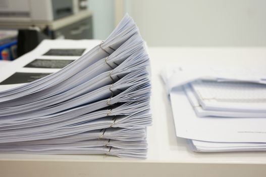 Pile of papers laid overlap on the desk in office.                               