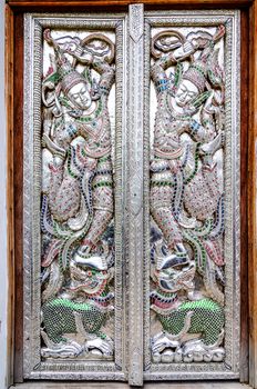 Ancient silver carving wooden doors of  temple in chiang mai ,Thailand.