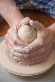 Hands of a potter, creating an earthen jar on the circle