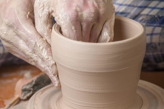 Hands of a potter, creating an earthen jar on the circle