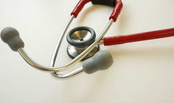 Red stethoscope placed on the table in the examination room.                        