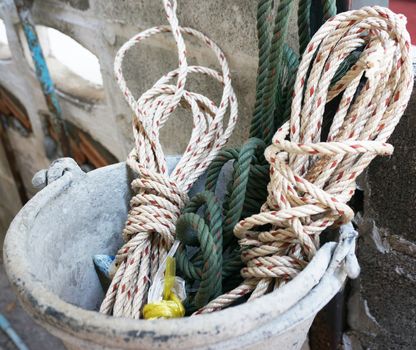 Pile of rope in old basket, put beside the cement wall.                         