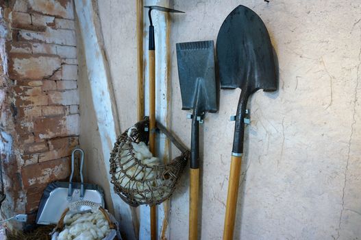 Farm equipment, gardening, resting against the wall behind the house, such as shovels, spades.                               