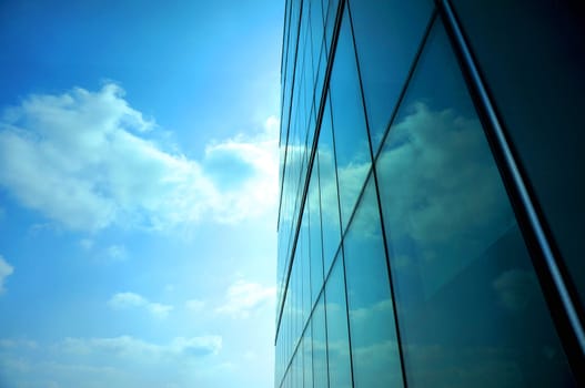 Tall buildings with modern style creating a mirror, reflecting the light from outside the building, reflecting  the clouds that floating by and the beautiful of blue sky.                               