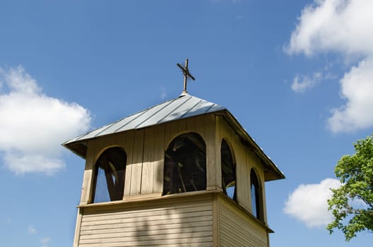 old wooden village church bell tower on blue spring sky background