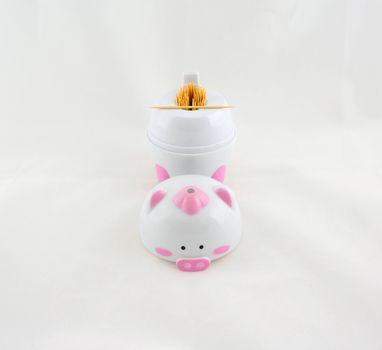 Wooden toothpick put in a container, shaped like a pig. Placed on a white background.                              