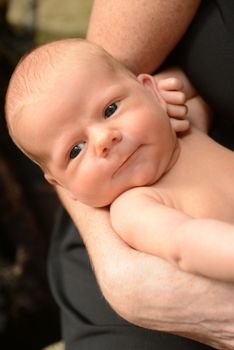 Happy and chubby newborn baby in mom's arms